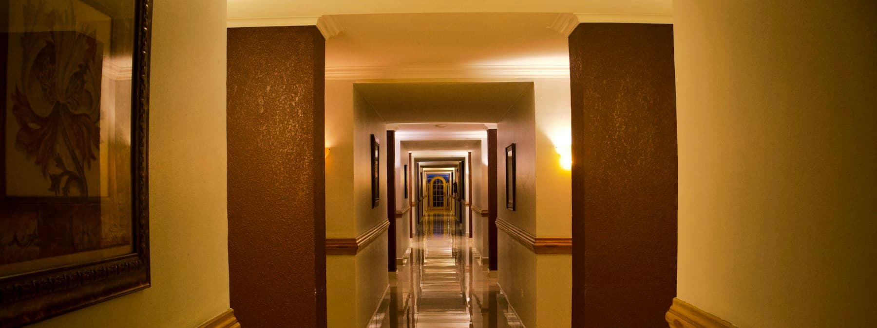 A lit hotel corridor lined with dark timber columns.