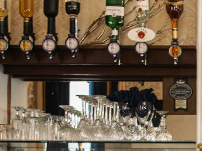 Spirit optics above a shelf of upturned stemware on a back bar.