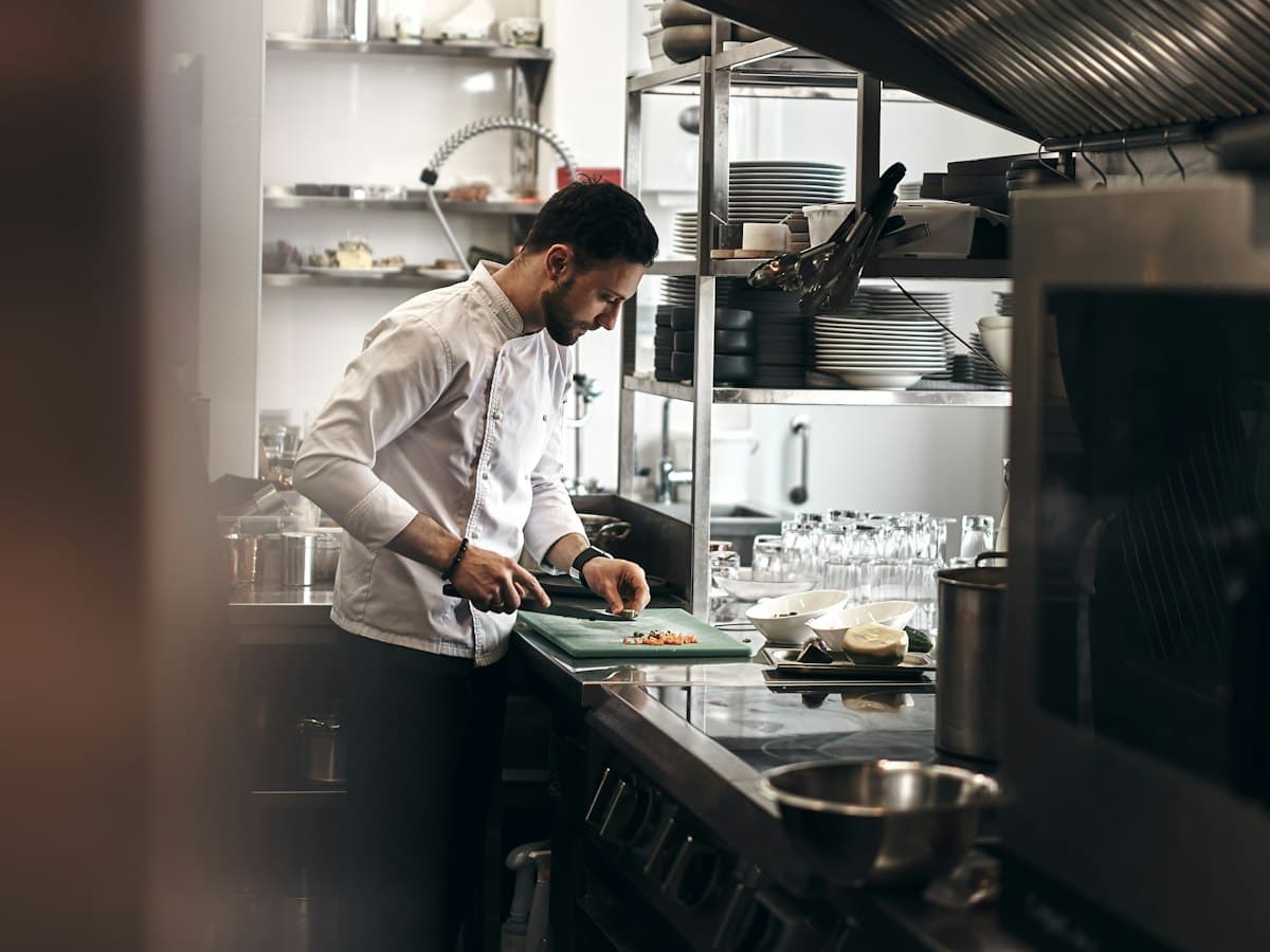A chef plating a dish at a kitchen pass.